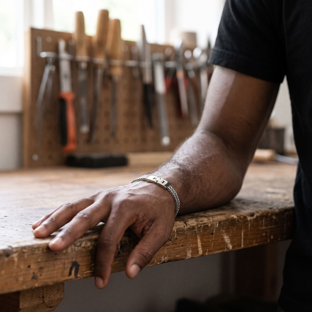 Foxtail Bracelet (Silver) on a man's wrist, his hand resting on a wooden workbench