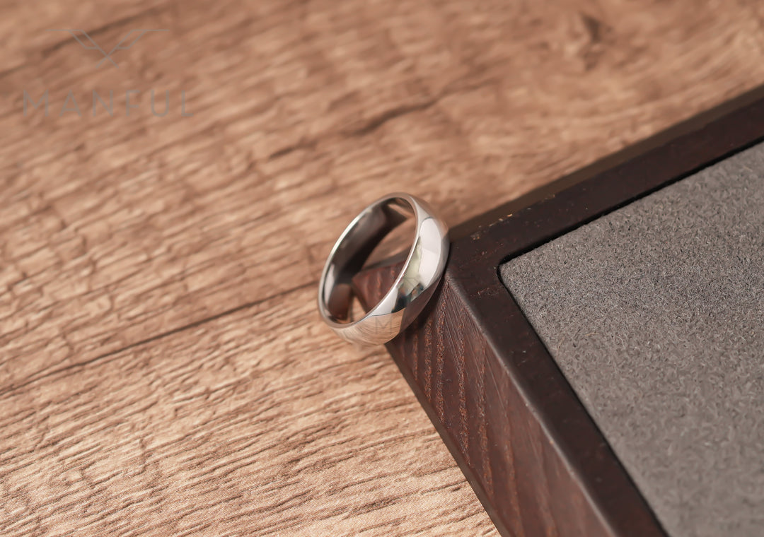 Simple 6mm 925 Silver Ring, leaning against a dark wooden block on a wood surface