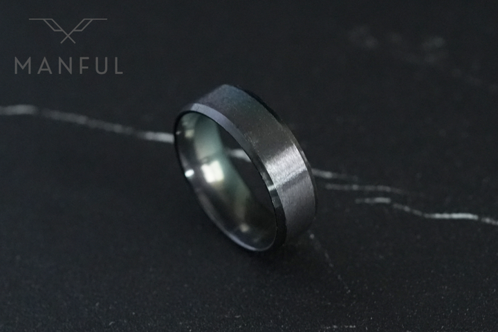 Simple Stainless Steel Ring 8mm Black, standing angled on dark marble with light veining
