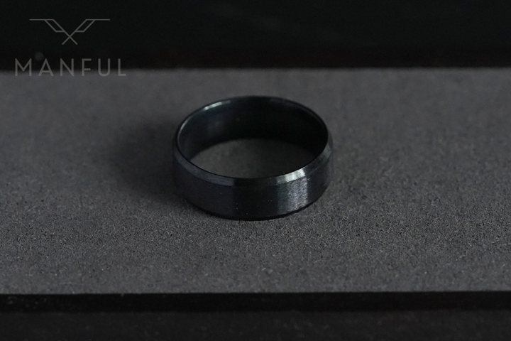 Simple Stainless Steel Ring 8mm Black, standing upright on a charcoal textured surface