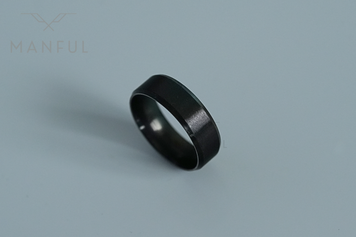Simple Stainless Steel Ring 8mm Black, standing angled on a plain pale blue-grey background