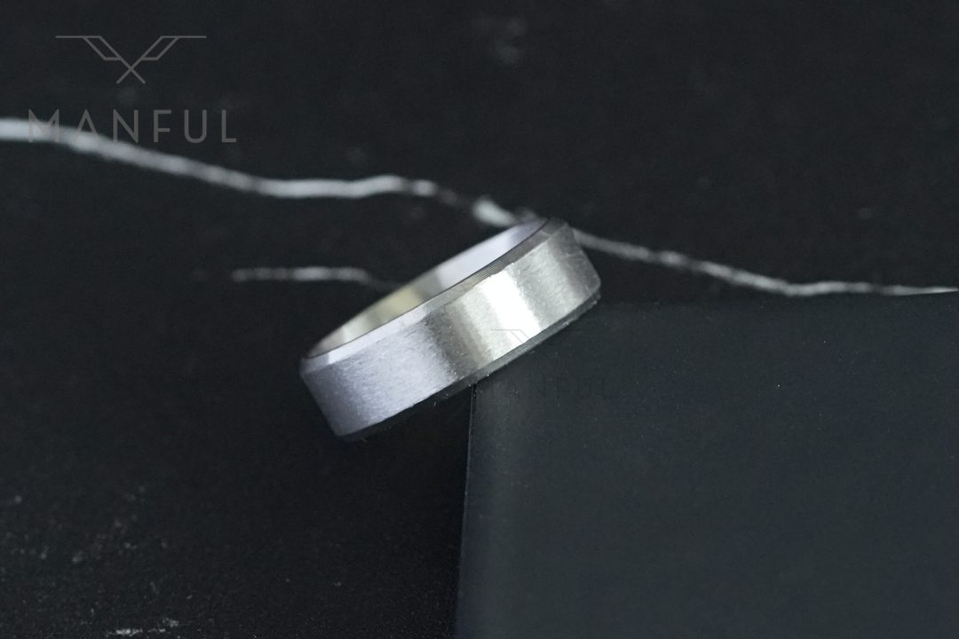 Simple Stainless Steel Ring 8mm Silver, resting on the corner of a black box against dark marble