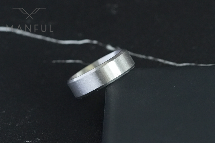 Simple Stainless Steel Ring 8mm Silver, resting on the corner of a black box against dark marble