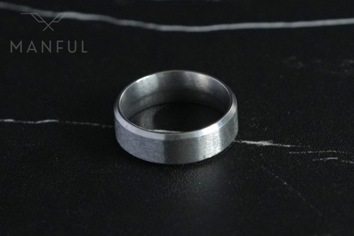 Simple Stainless Steel Ring 8mm Silver, lying flat on a dark veined marble surface