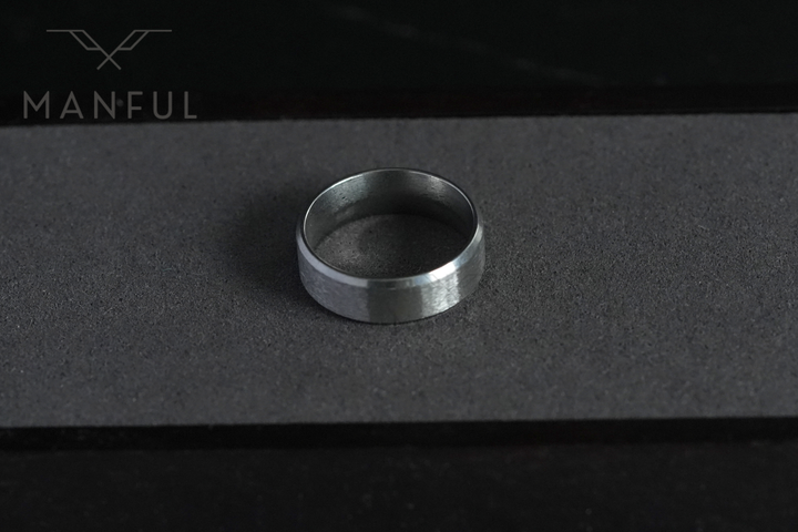 Simple Stainless Steel Ring 8mm Silver, standing on a charcoal grey suede strip in low light