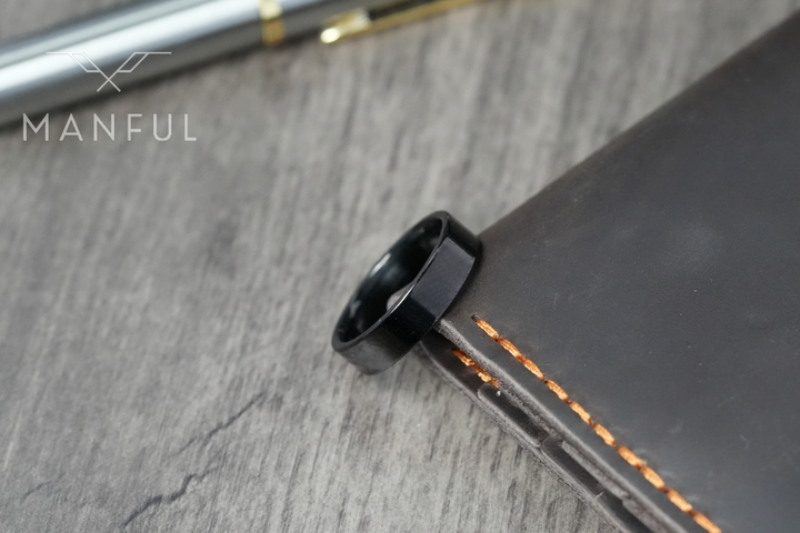 Simple 6mm Ring Black, resting on the edge of a leather journal beside a pen