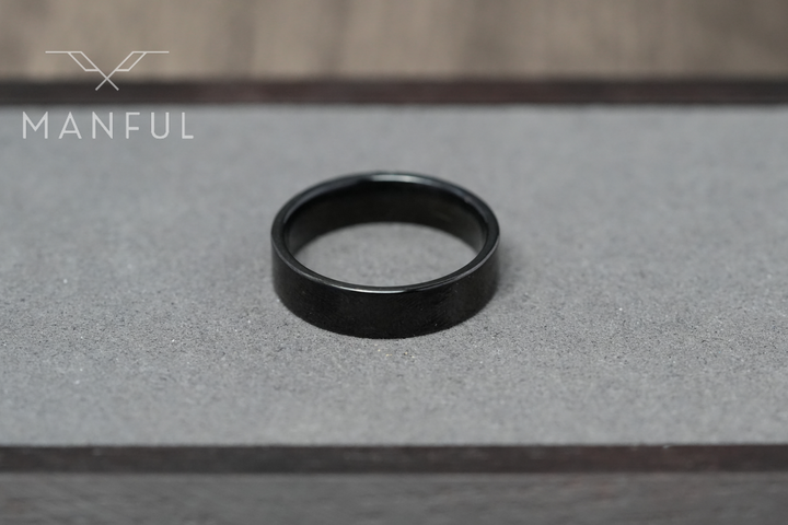 Simple 6mm Ring Black, lying flat on a light grey stone surface