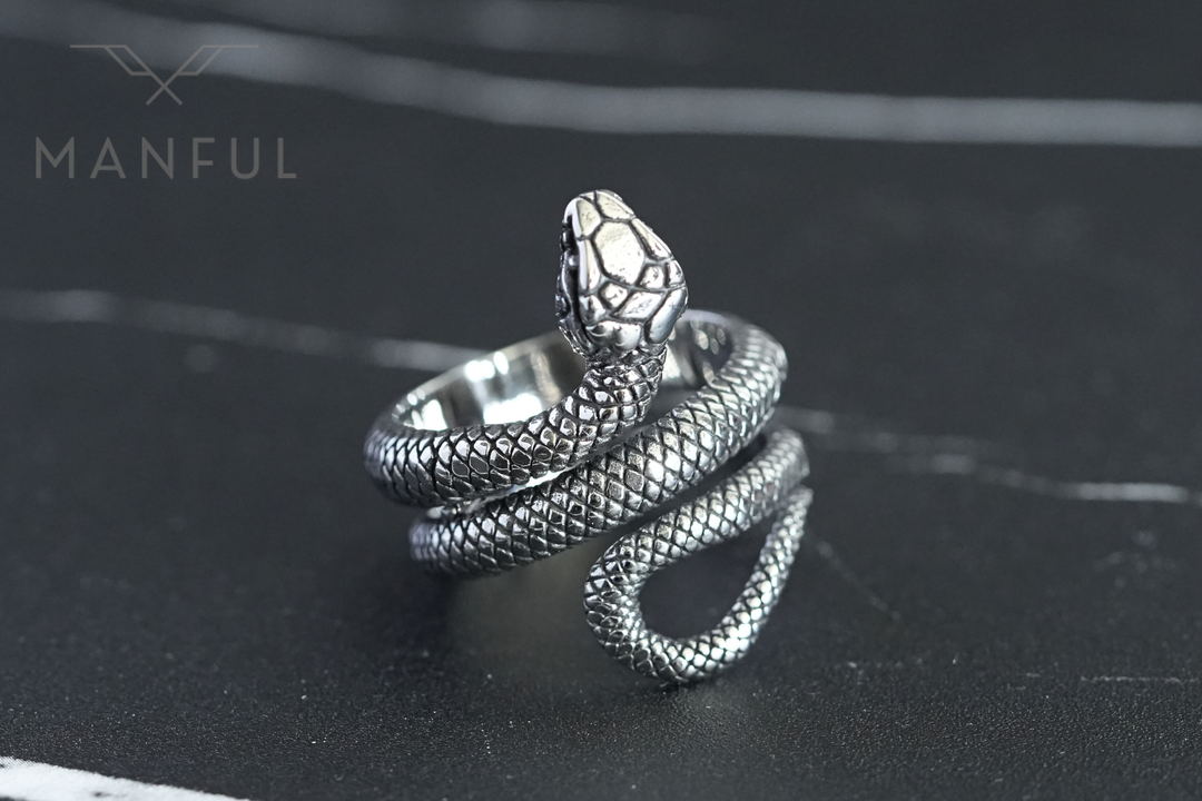 Snake Ring, coiled on a dark stone surface with a white marble vein behind it