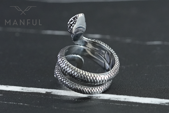 Snake Ring, tilted to show the coil from above on a dark marble surface