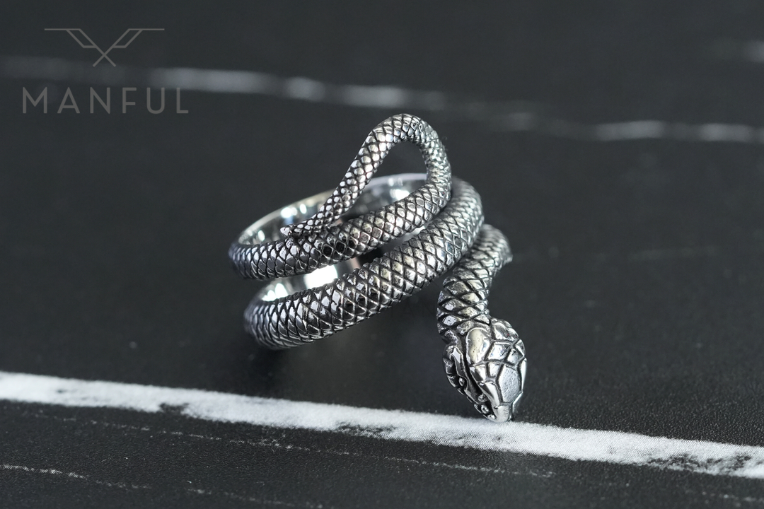 Snake Ring, head resting beside a white marble vein on a dark stone surface