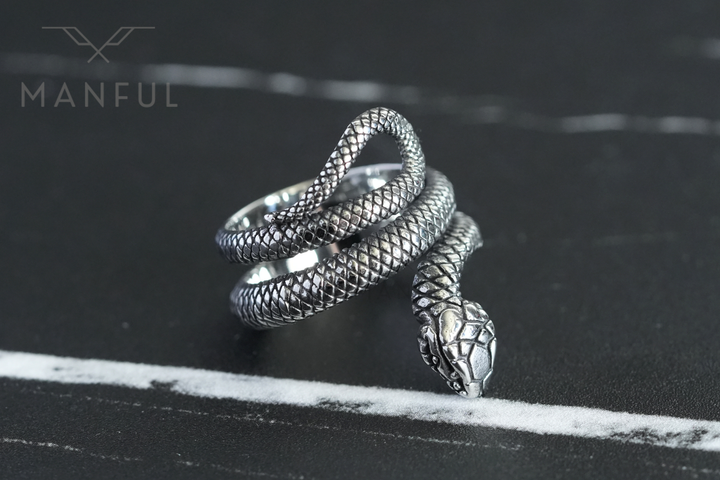 Snake Ring, head resting beside a white marble vein on a dark stone surface