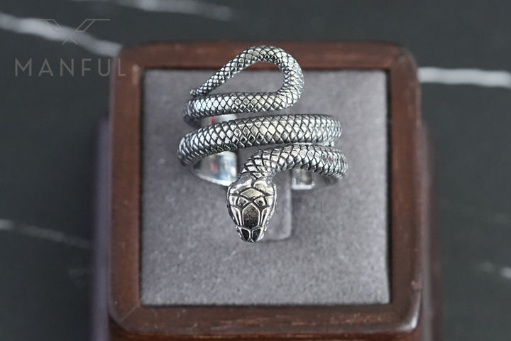 Snake Ring, resting in a wooden ring box on a grey velvet cushion