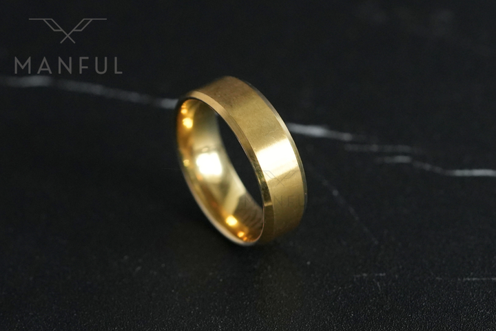 Simple Stainless Steel Ring 8mm Gold, tilted on its edge on a dark marble surface