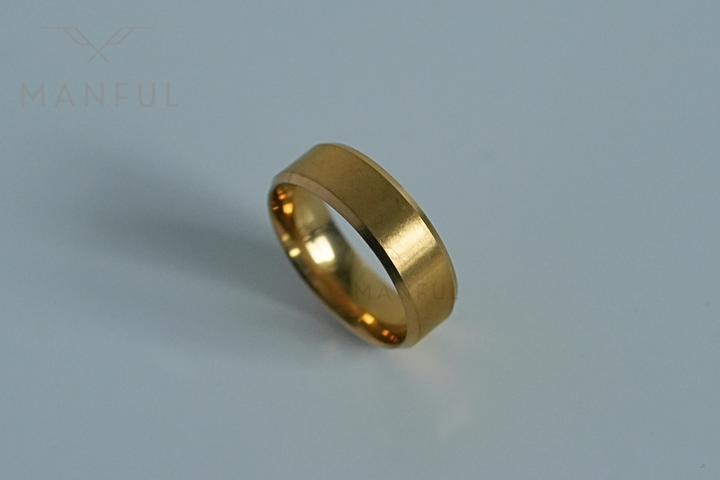 Simple Stainless Steel Ring 8mm Gold, angled on a plain light grey surface
