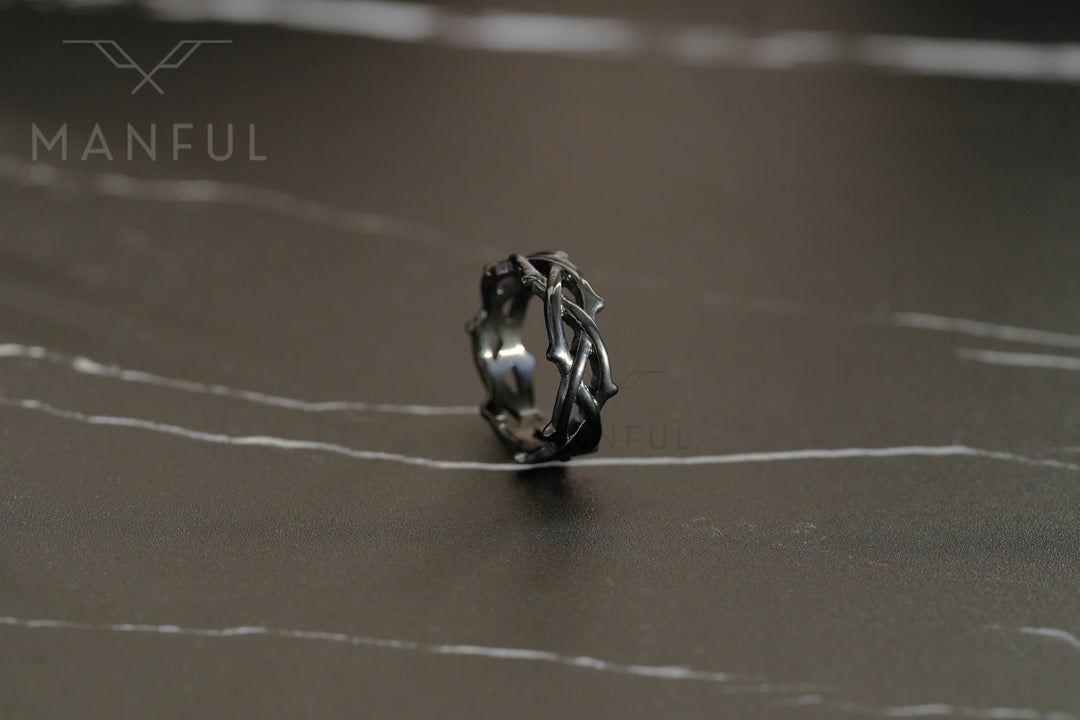 Thorn Ring Black, standing on a dark reflective surface with a blurred background