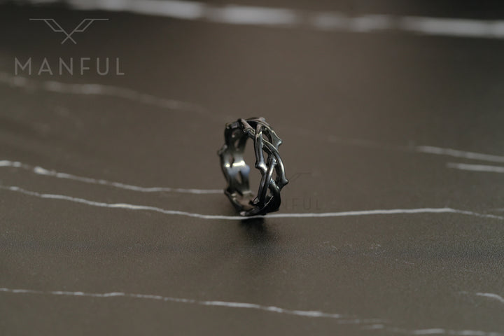 Thorn Ring Black, standing on a dark reflective surface with a blurred background