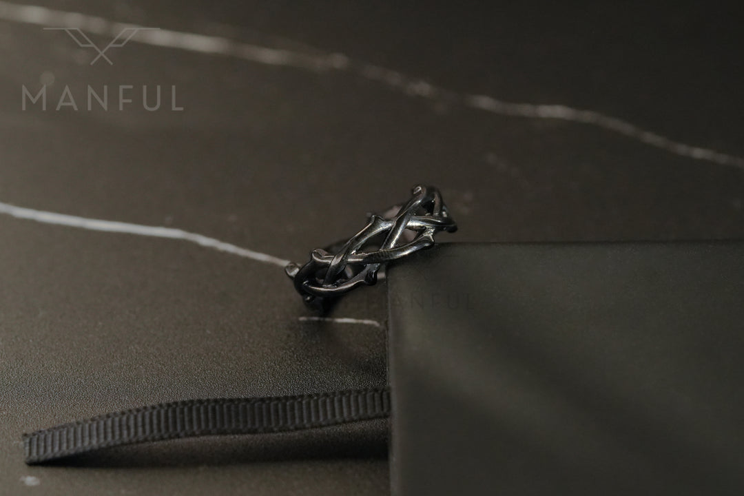 Thorn Ring Black, resting on a black ribbon edge beside a black box