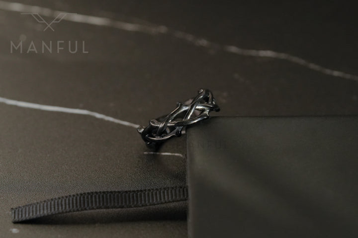 Thorn Ring Black, resting on a black ribbon edge beside a black box