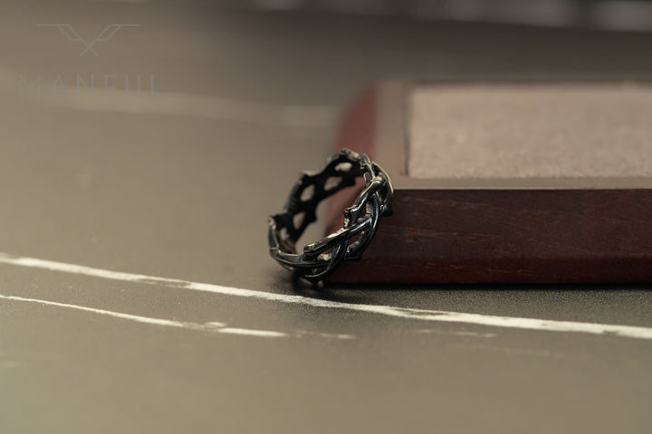 Thorn Ring Black, resting on a surface beside a wood-edged tray