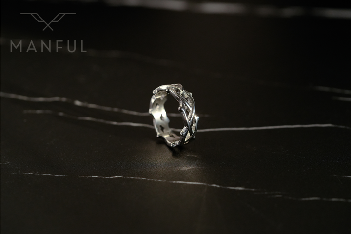 Thorn Ring Silver, standing upright on a dark marble surface in a wide shot