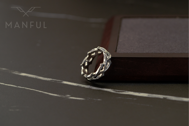 Thorn Ring Silver, resting on a dark marble surface against a dark wooden box