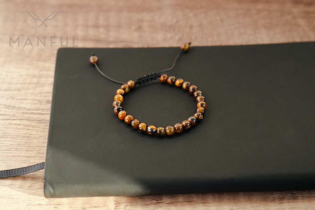 Tigers Eye Bead Bracelet, resting on a dark flat case on a wood tabletop
