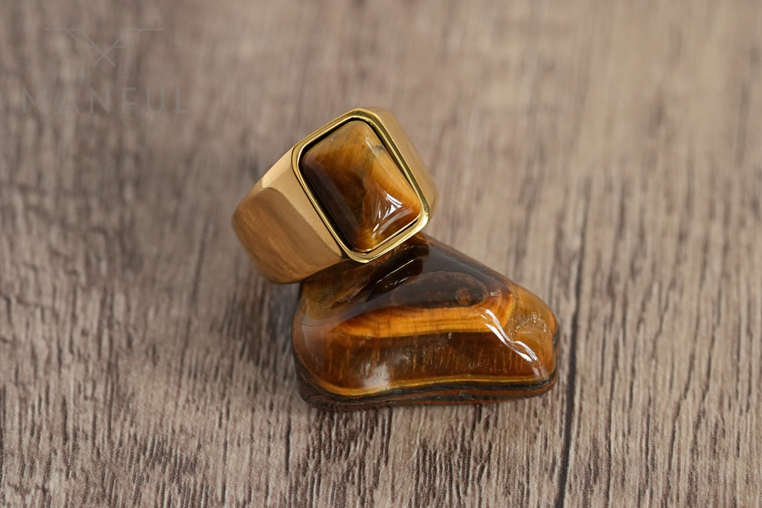 Tigers Eye Signet Ring Gold, coiled snake ring angled on a dark marble surface