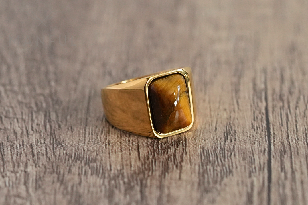 Tigers Eye Signet Ring Gold, shot from a low tilted angle on dark marble