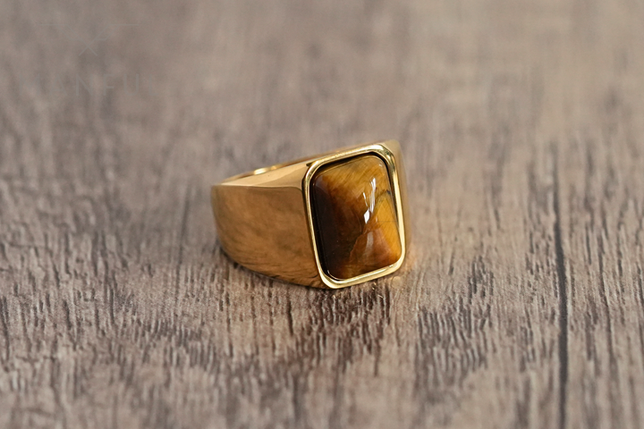 Tigers Eye Signet Ring Gold, shot from a low tilted angle on dark marble