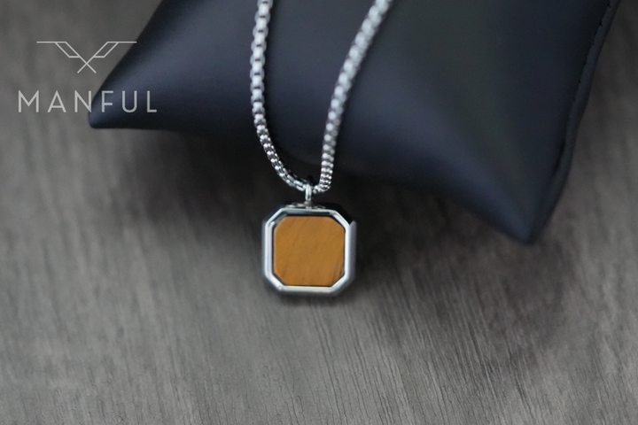 Tigers Eye Square Necklace Silver, draped over a black leather cushion on wood