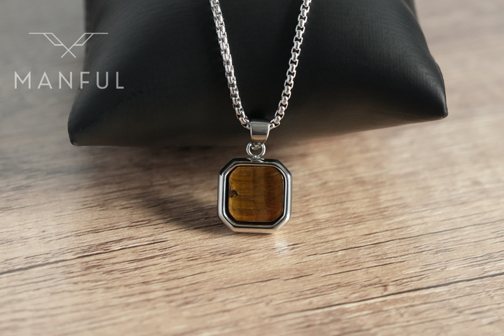 Tigers Eye Square Necklace Silver, draped over a black cushion on a wooden table