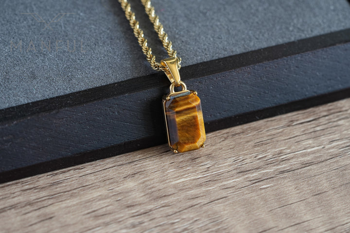 Tigers Eye Stone Pendant Gold, draped over a dark box edge on a wood surface