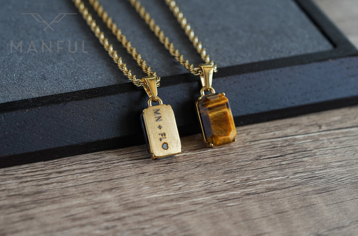 Tigers Eye Stone Pendant Gold, paired with an engraved name tag pendant on a dark box edge