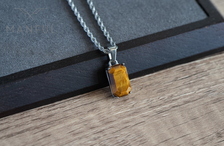 Tigers Eye Stone Pendant Silver, resting on a wood surface beside a dark box corner