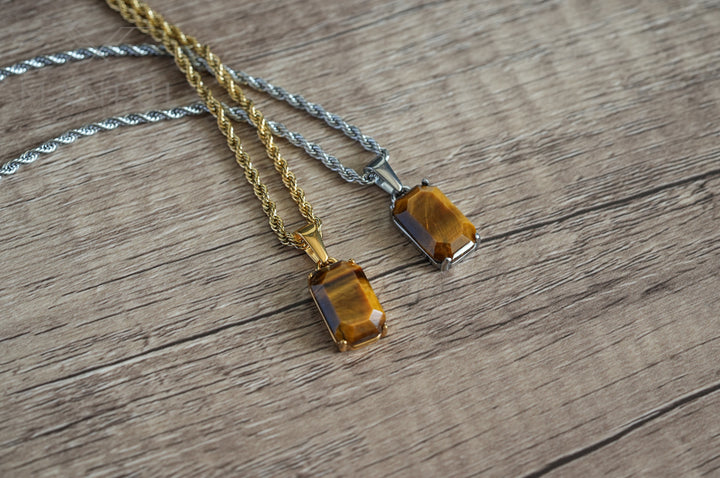 Tigers Eye Stone Pendant Silver, shown on wood beside a matching pendant on a gold chain