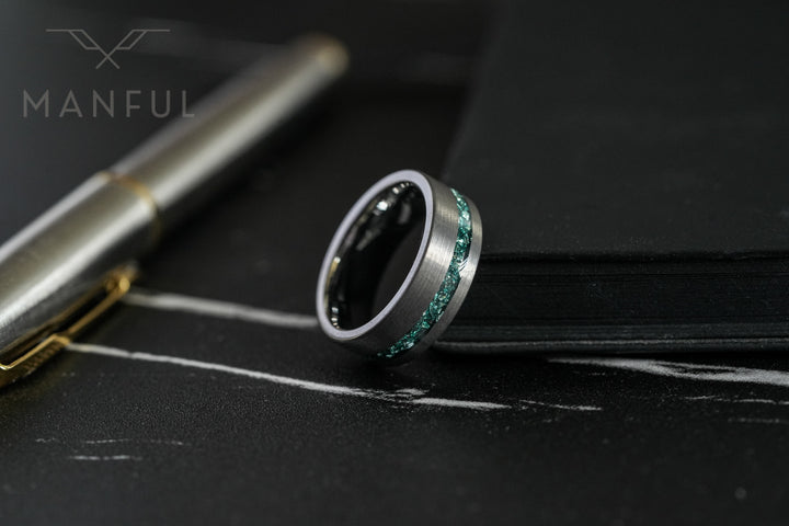 Tungsten Aquamarine Inlay Band Silver, resting beside a blurred pen near a dark leather book