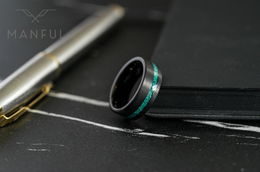 Tungsten Malachite Inlay Band Black, resting on dark marble beside a pen and notebook