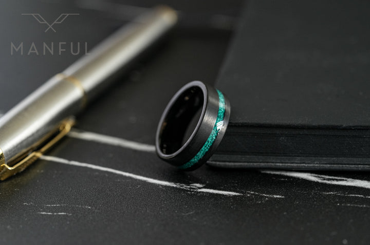Tungsten Malachite Inlay Band Black, resting on dark marble beside a pen and notebook