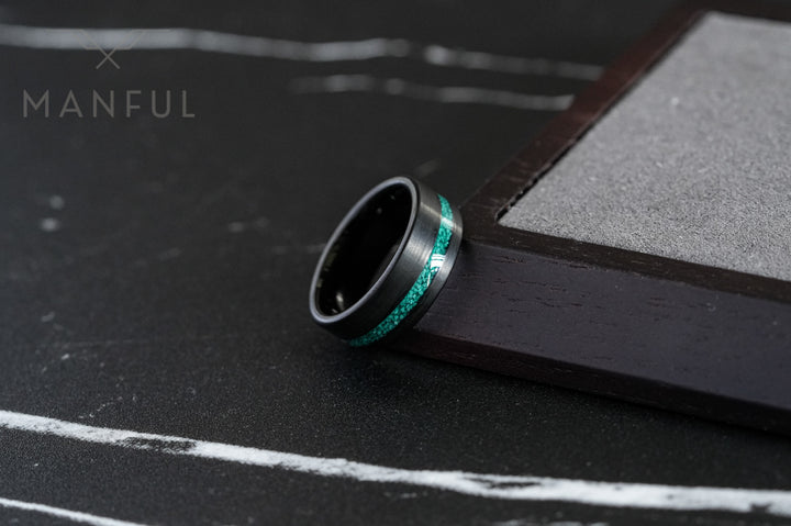 Tungsten Malachite Inlay Band Black, leaning upright against a wooden box on dark marble