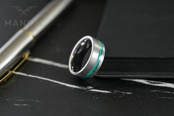 Tungsten Malachite Inlay Band Silver, resting on a black notebook beside a fountain pen