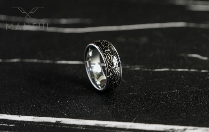Meteorite Fragment Ring, standing upright on dark slate with the polished silver interior visible