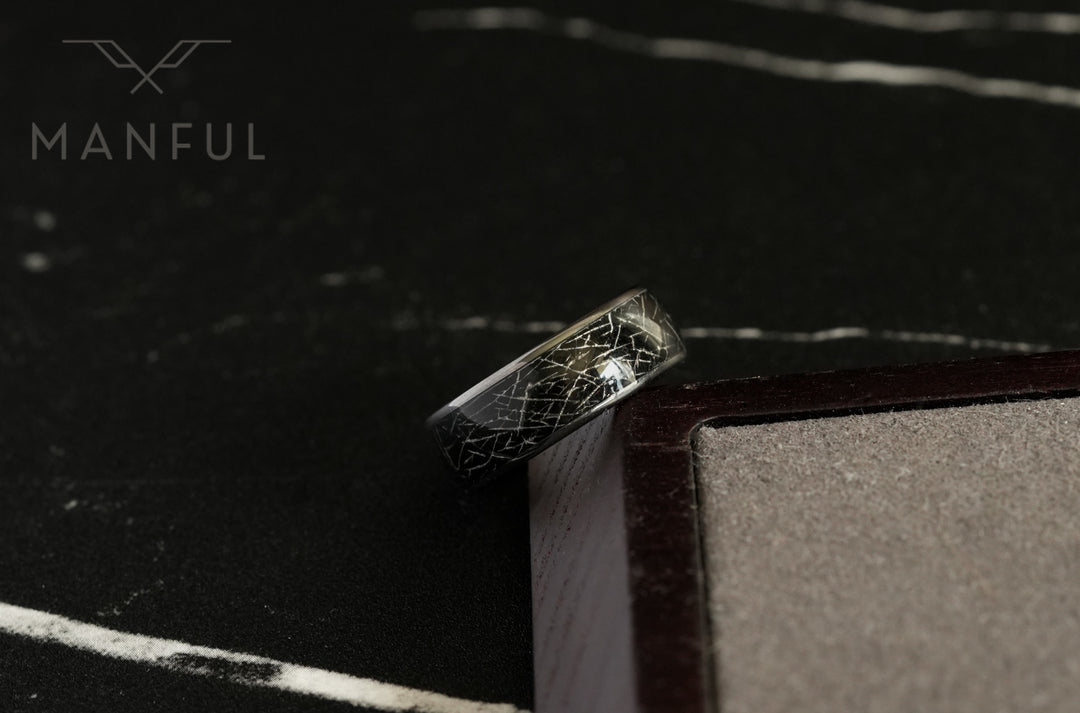 Meteorite Fragment Ring, propped against a dark leather book corner on dark slate