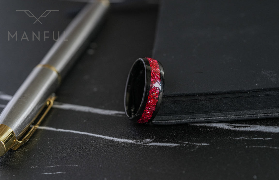 Tungsten Red Opal Black Band, laid on its side on a marble surface beside a pen