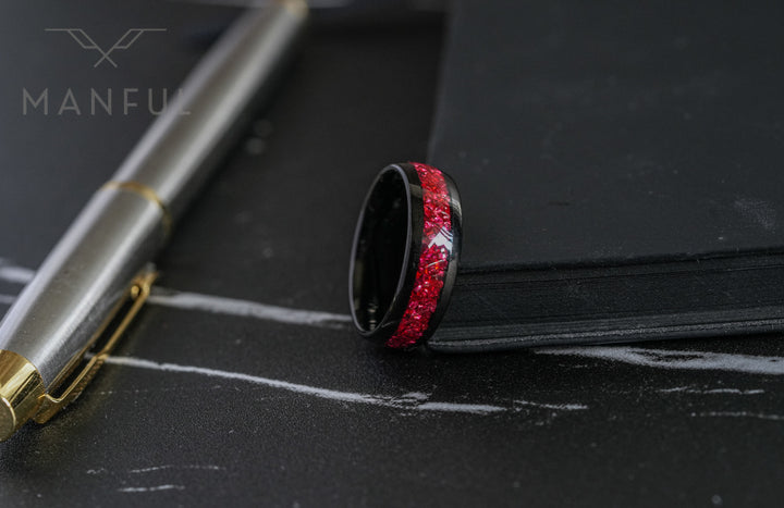 Tungsten Red Opal Black Band, laid on its side on a marble surface beside a pen