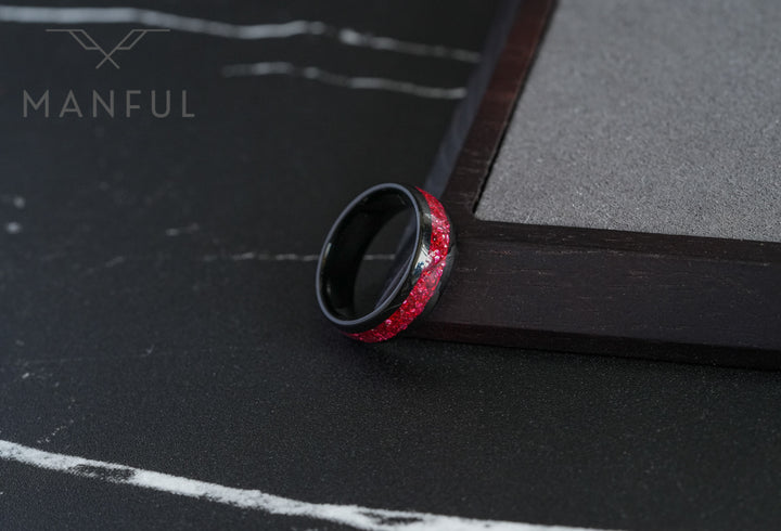 Tungsten Red Opal Black Band, propped against a dark wooden block edge on a black textured surface