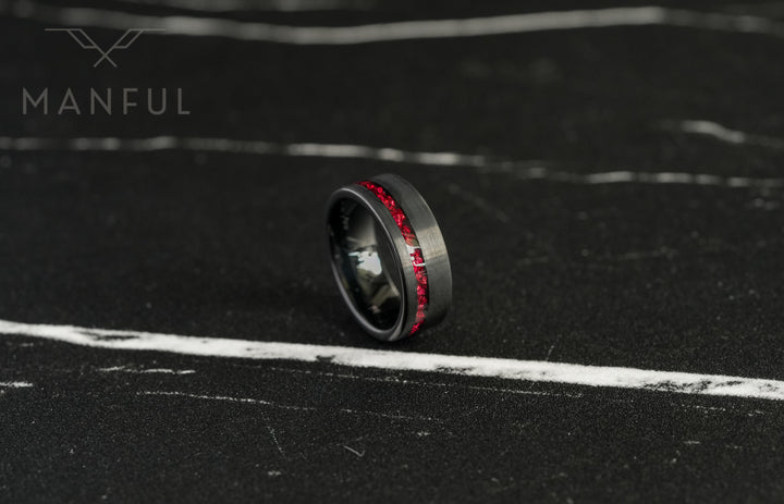 Tungsten Red Opal Inlay Band Black, tilted on a dark stone surface with the red inlay stripe close up