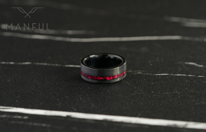 Tungsten Red Opal Inlay Band Black, resting flat on a dark marble surface with the red inlay facing forward