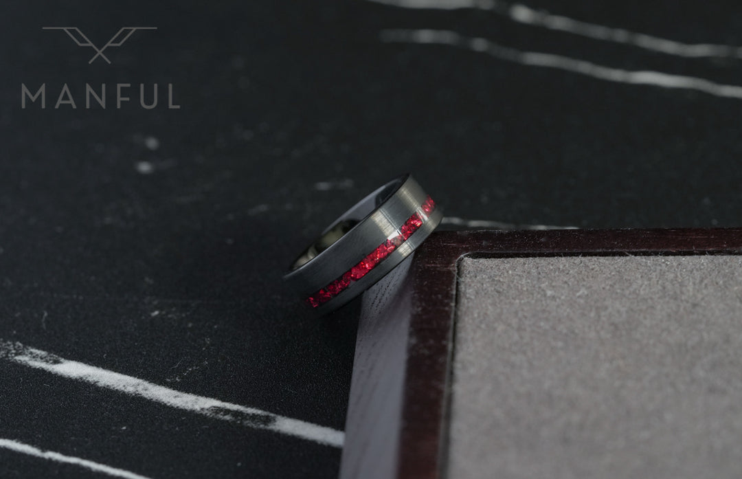 Tungsten Red Opal Inlay Band Black, tilted against a dark book corner on a marble surface