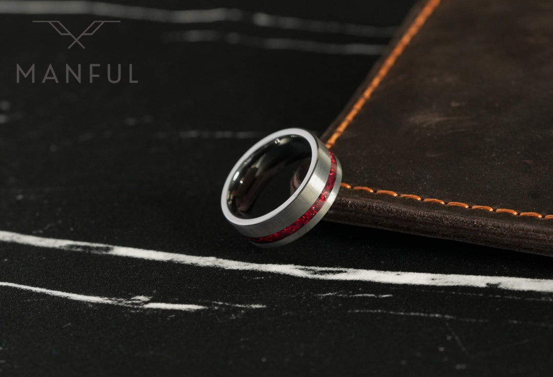 Tungsten Red Opal Inlay Band Silver, leaning against a stitched leather journal on marble