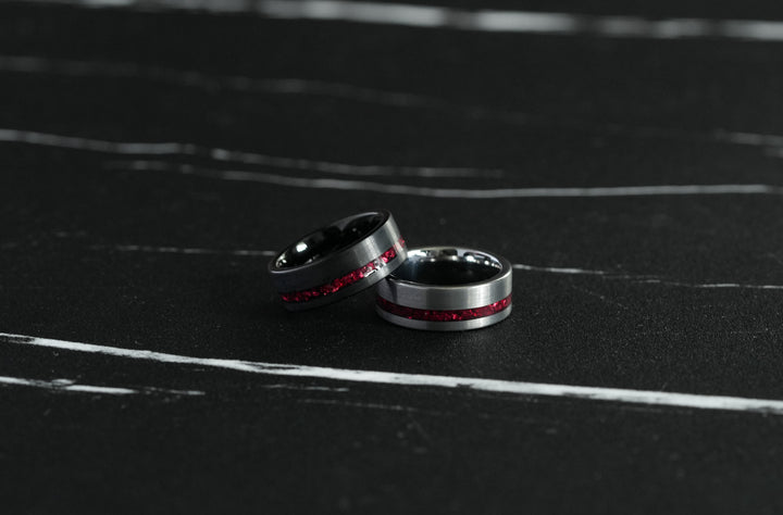 Tungsten Red Opal Inlay Band Black, paired with a second matching ring on a dark marble surface